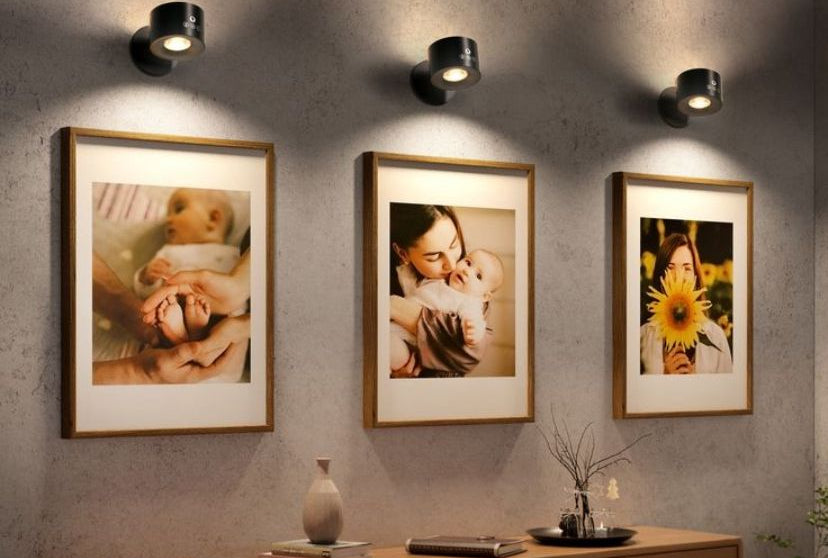 Three framed photographs on a wall above a wooden cabinet.